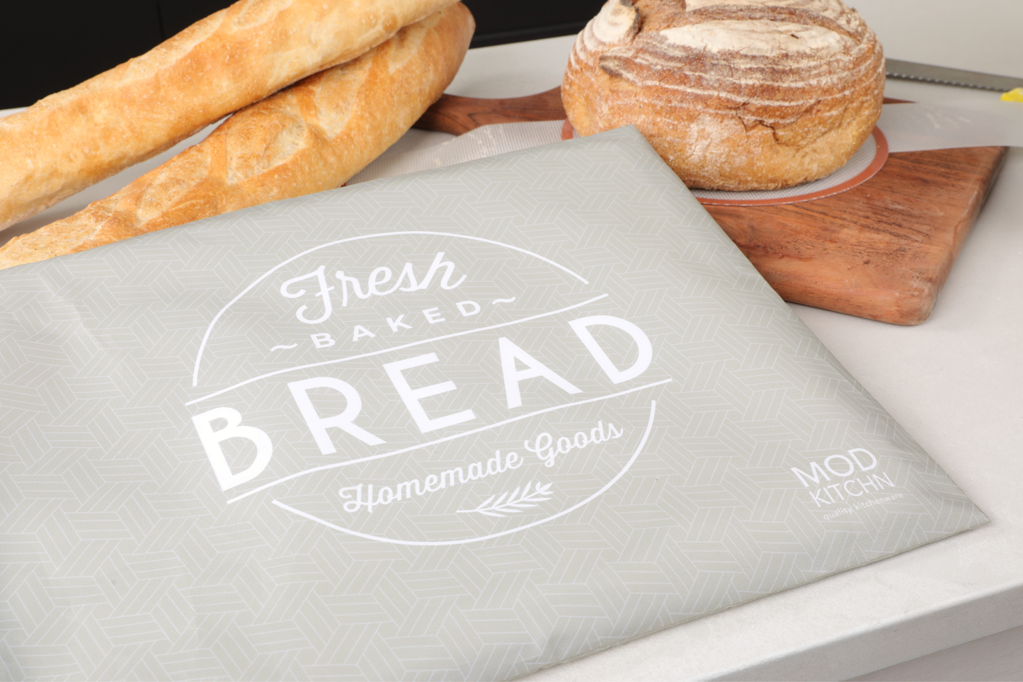 Gray bread bag with 'Fresh Baked Bread' text, placed on a table with bread and a knife.