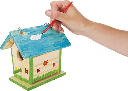 Hand painting a wooden birdhouse with blue paint on a white background