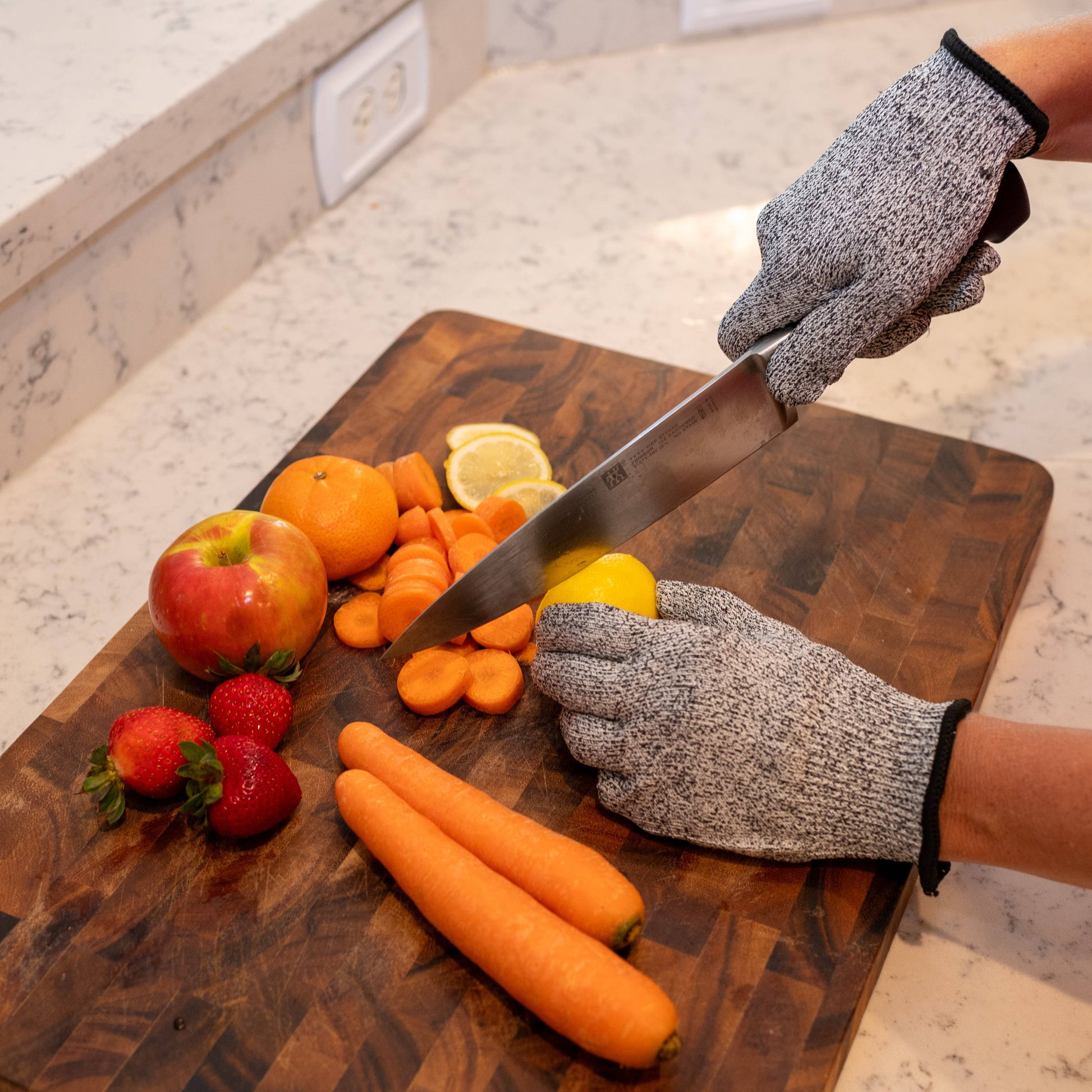 Person wearing cut-resistant gloves cutting vegetables on a wooden cutting board.