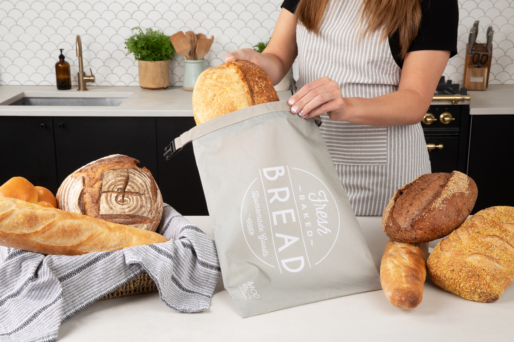 Person holding a bread bag with bread displayed around in a kitchen setting