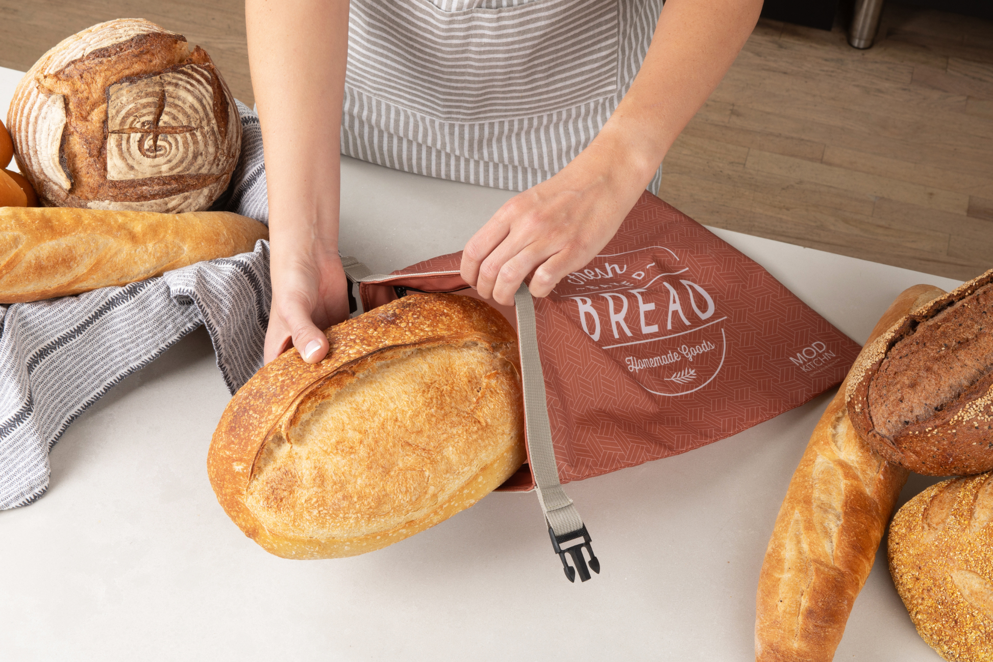 Person holding a loaf of bread with a 'Bread' bag in the background