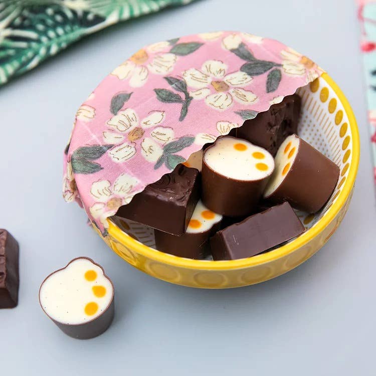 Chocolate candies in a floral-patterned bowl on a light blue surface