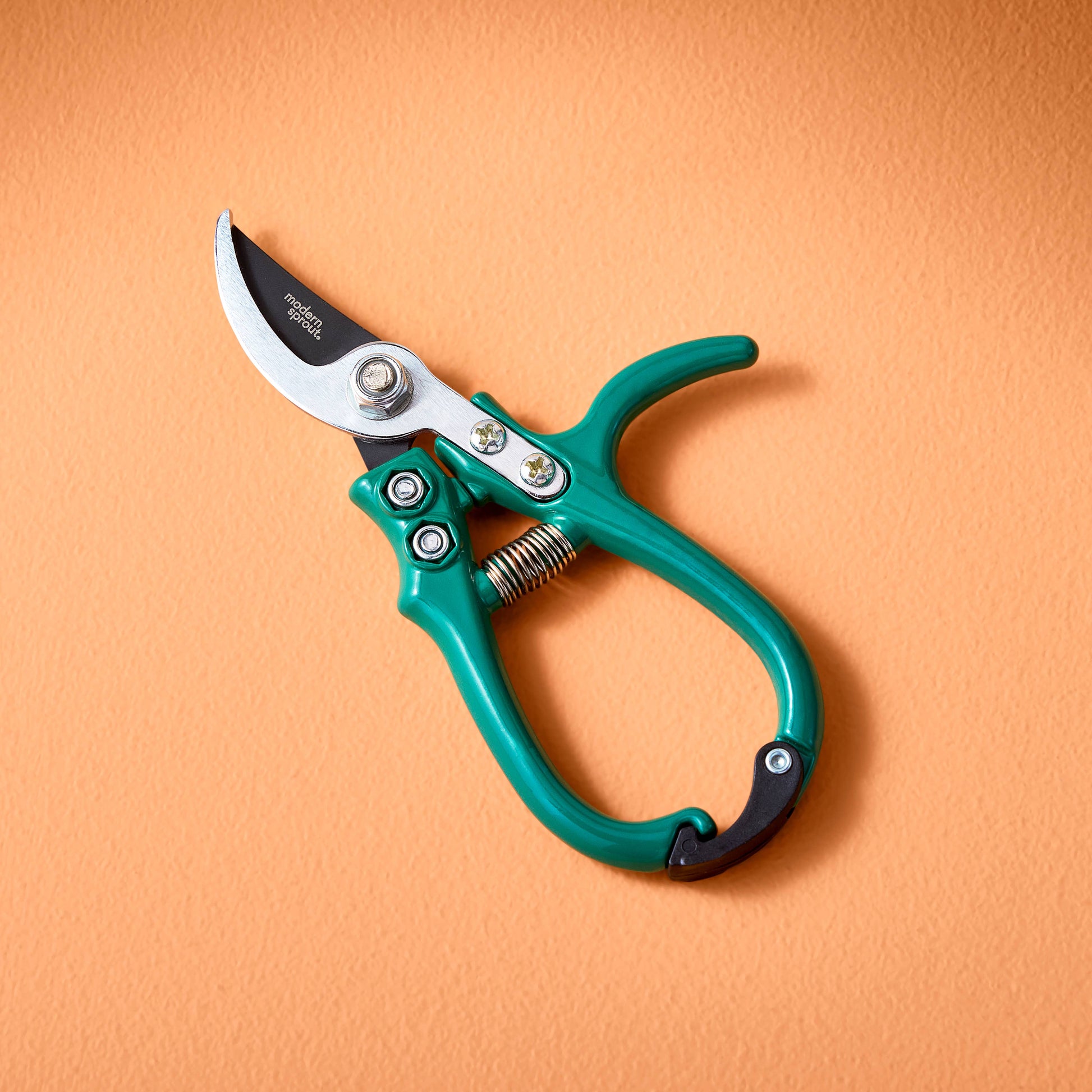 Teal garden pruner on an orange background